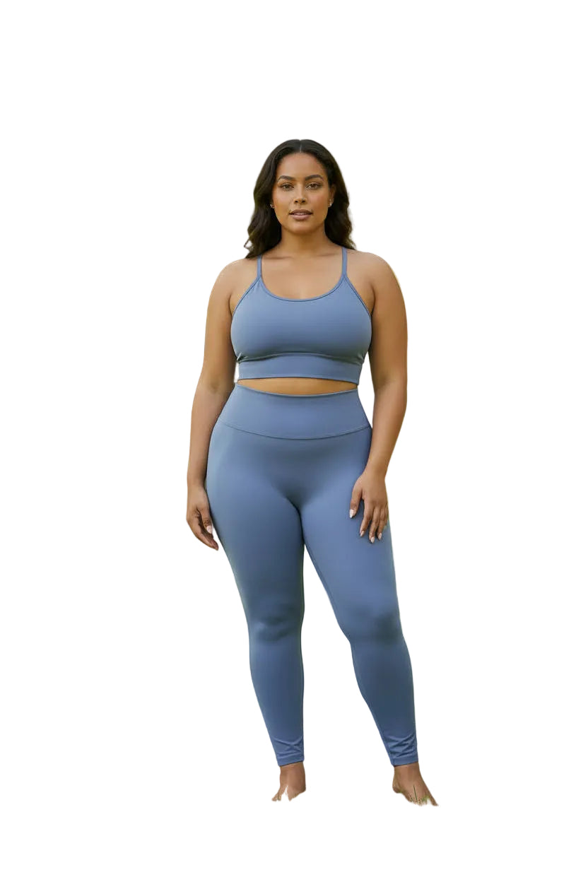 A two-piece athletic set in dusty periwinkle blue displayed on a headless mannequin torso. The set includes a ribbed halter-neck bodysuit and matching high-waisted leggings.