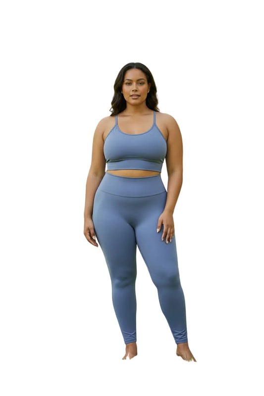 A two-piece athletic set in dusty periwinkle blue displayed on a headless mannequin torso. The set includes a ribbed halter-neck bodysuit and matching high-waisted leggings.