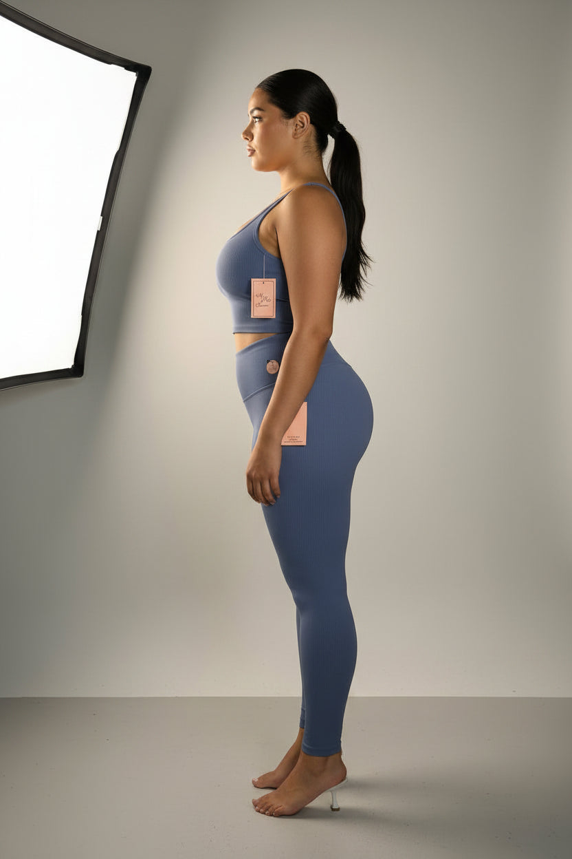 A two-piece activewear set in dusty blue, displayed on a white dress form mannequin. The set includes a sleeveless scoop-neck top and matching high-waisted leggings.